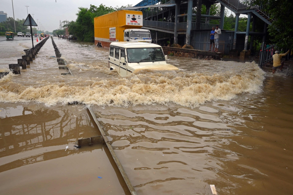 A commuter drives his car along a flooded highway after heavy monsoon rains in Gurgaon on the outskirts of New Delhi on July 9, 2023. Photo by AFP