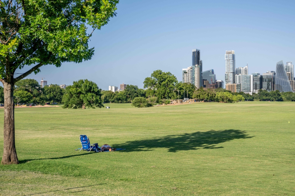A person rests in the shade at Zilker Metropolitan Park on July 10, 2023 in Austin, Texas. (Photo by Brandon Bell/Getty Images/AFP)


