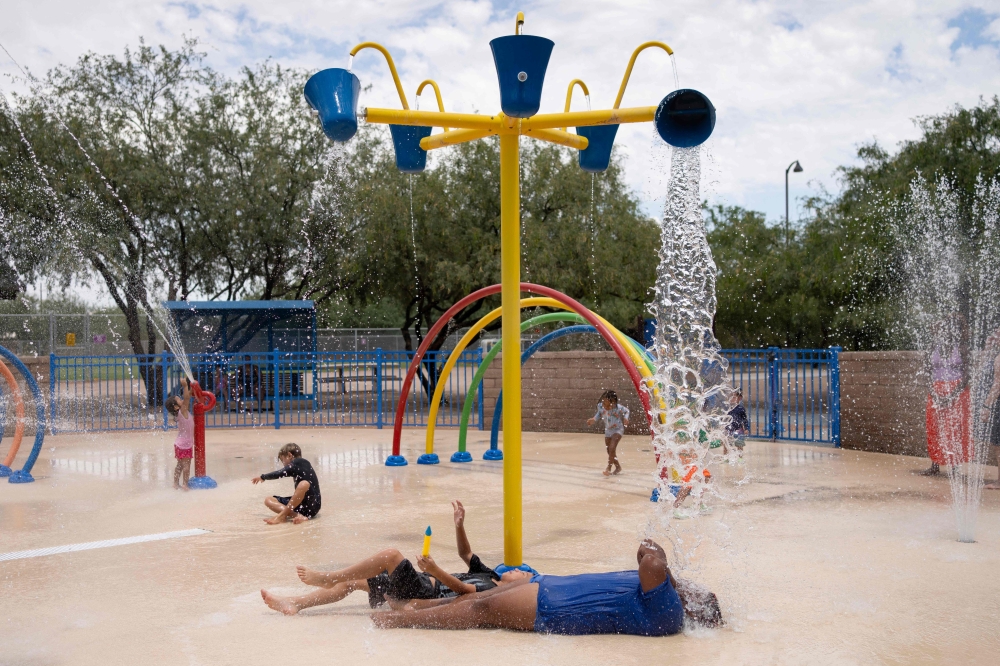 Residents frolic in the splash pad at Brandi Fenton Memorial Park during a heat wave in Tucson, Arizona, on July 15, 2023.  Photo by Rebecca NOBLE / AFP
