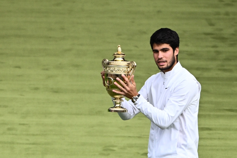 Spain's Carlos Alcaraz raises the winner's trophy after beating Serbia's Novak Djokovic during their men's singles final tennis match on the last day of the 2023 Wimbledon Championships at The All England Tennis Club in Wimbledon, southwest London, on July 16, 2023. (Photo by SEBASTIEN BOZON / AFP)