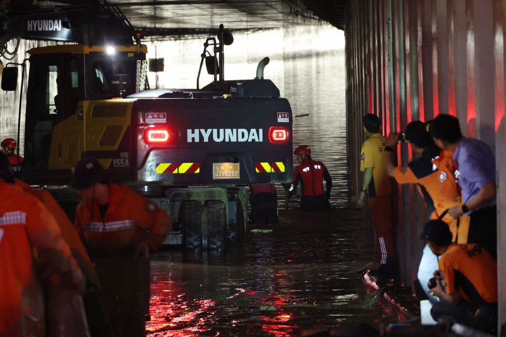 Rescue workers search for missing people along an underground tunnel, where some 15 cars were trapped in floodwaters after heavy rains, in Cheongju early on July 17, 2023. Photo by YONHAP / AFP