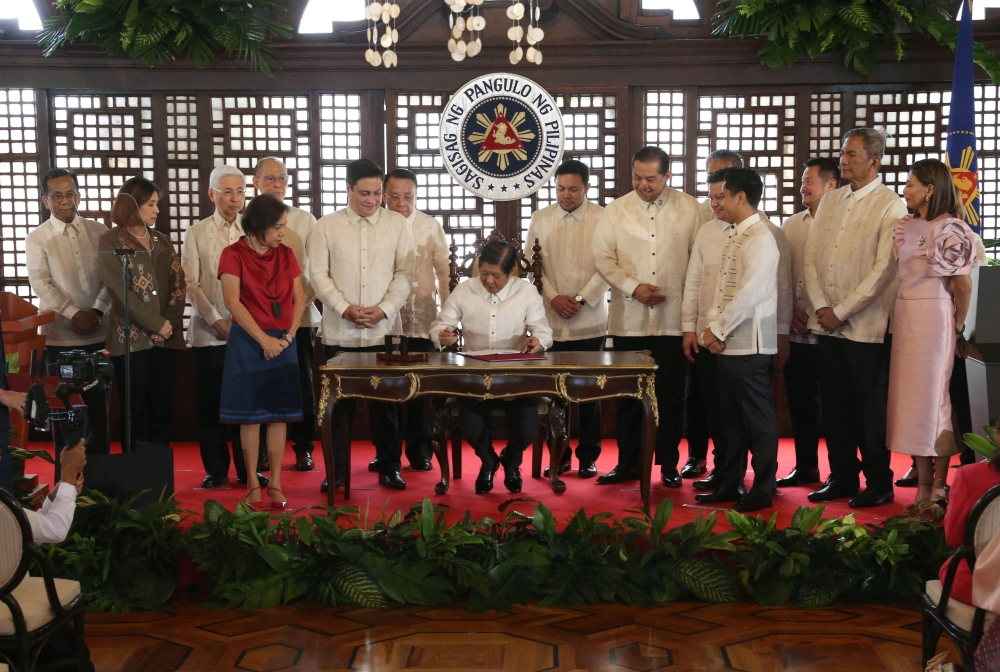 This handout photo taken and recieved by the Philippines' Presidential Photographers Association (PPA) on July 18, 2023 shows Philippines President Ferdinand Marcos Jr. (C) signing the Maharlika sovereign wealth fund into law at the Malacanang Palace in Manila. Photo by Handout / Philippines Presidential Photographers Association (PPA) / AFP