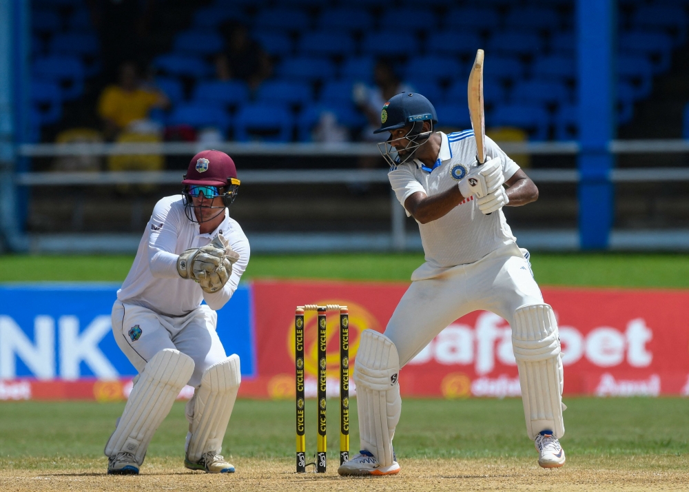 Ravichandran Ashwin (R) of India hits 4 and Joshua Da Silva (L) of West Indies watche during the second day of the second Test cricket match between India and West Indies at Queen's Park Oval in Port of Spain, Trinidad and Tobago, July 21, 2023. (Photo by Randy Brooks / AFP)