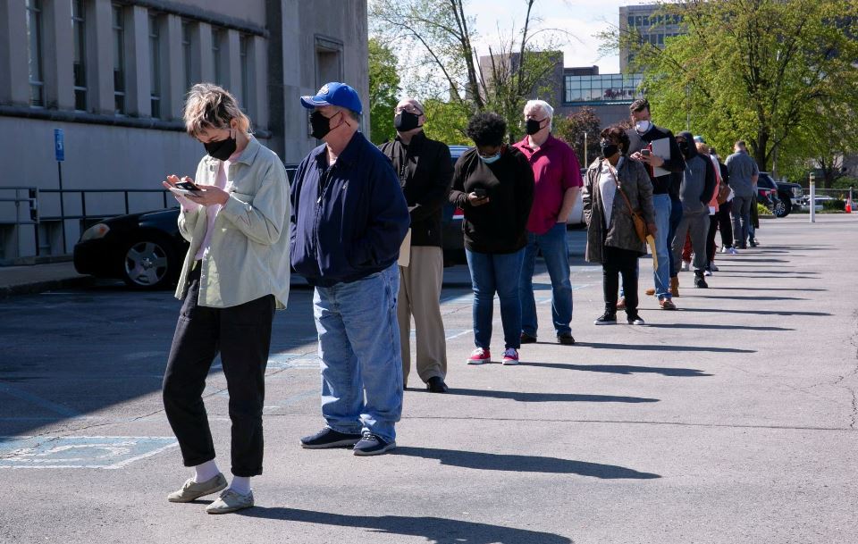 A file photo of people lining up outside a career center for in-person appointments in Louisville, US.