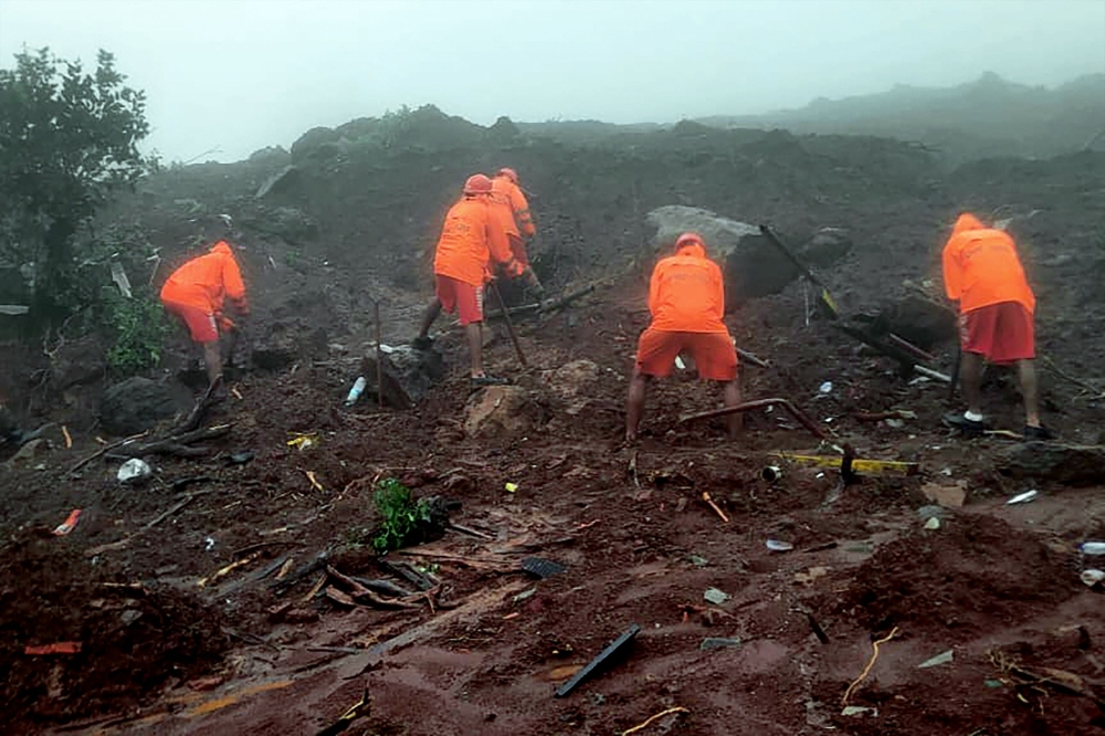 In this handout photograph released by India痴 National Disaster Response Force (NDRF) and taken on July 23, 2023, NDRF personnel search for victims at the site of a landslide at Irshalwadi village of Raigad district in Maharashtra state. Photo by AFP