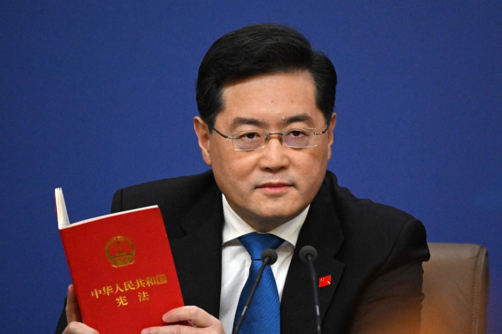 (Files) China's Foreign Minister Qin Gang holds a copy of China's constitution during a press conference at the Media Center of the National People's Congress (NPC) in Beijing on March 7, 2023. (Photo by Noel Celis / AFP)