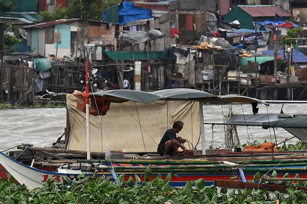 A man secures his boat at Baseco in Manila on July 26, 2023, as Super Typhoon Doksuri passes close to the northern tip of Luzon island. (Photo by Jam Sta Rosa / AFP)