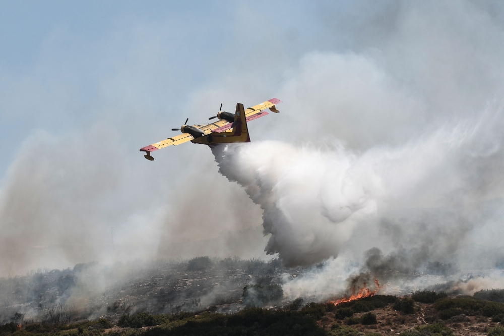 A canadair drop water onto a wildfire near the city of Volos, central Greece, on July 27, 2023. Photo by Sakis MITROLIDIS / AFP