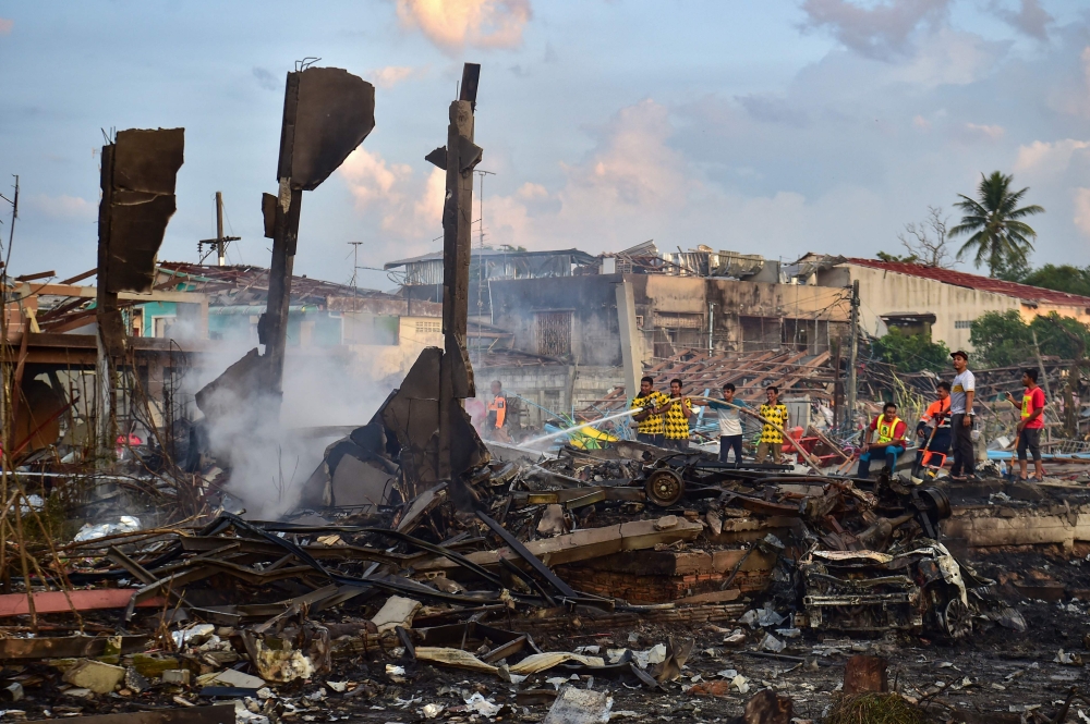 Thai firefighters put out embers around destroyed homes after an explosion ripped through a firework warehouse, killing nine people and injuring more than 100, in Sungai Kolok district in the southern Thai province of Narathiwat on July 29, 2023. Photos by Madaree TOHLALA / AFP