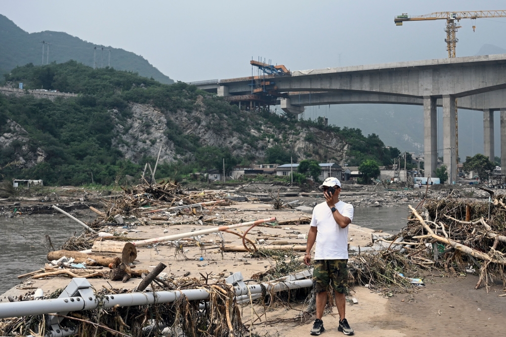 A man stands on a broken bridge at a flood-affected area following heavy rains in Beijing on August 3, 2023. Photo by Jade Gao / AFP