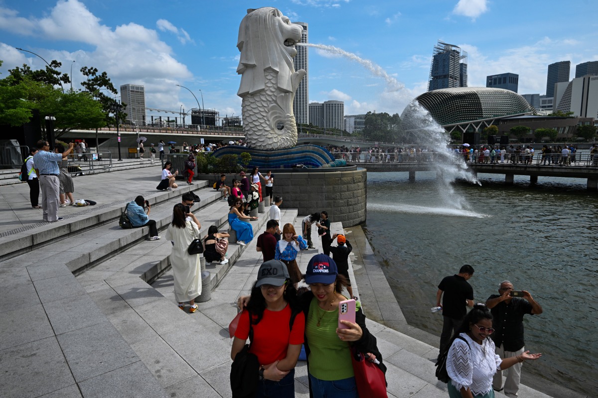 Tourists visit the Merlion Statue at Marina Bay in Singapore on July 31, 2023. (Photo by Mohd RASFAN / AFP)