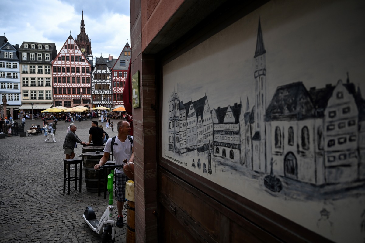 A man with a scooter looks at a street cafe at the Roemerberg square in central Frankfurt am Main, western Germany, on July 26, 2023. (Photo by Kirill KUDRYAVTSEV / AFP)
