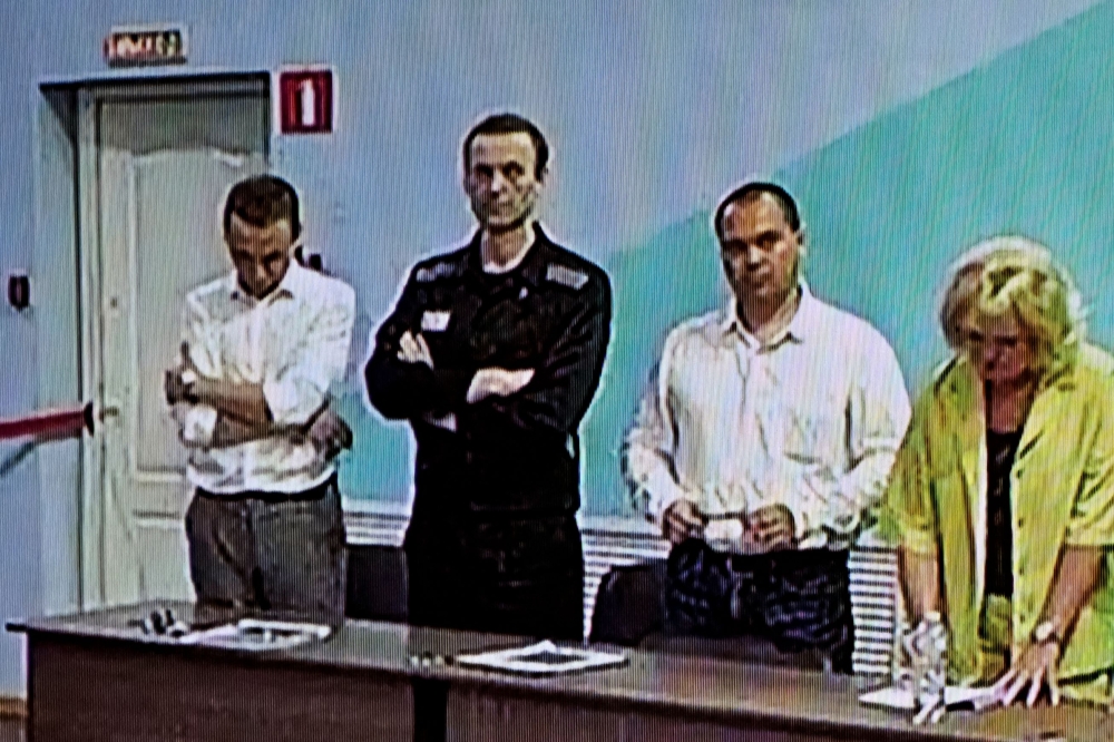 A screen shows the already imprisoned Russian opposition figure Alexei Navalny (2L) as he listens to his verdict over a series of extremism charges at the IK-6 penal colony, a maximum-security prison some 250 kilometres (155 miles) east of Moscow, in the settlement of Melekhovo in the Vladimir region on August 4, 2023. (Photo by Alexander NEMENOV / AFP)
