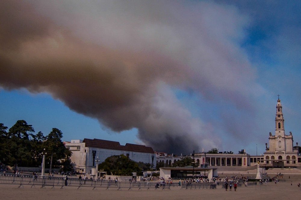 A column of smoke billows above the Sanctuary of Our Lady of Fatima, after a wildfire broke out in Fatima on August 5, 2023. Photo by CARLOS COSTA / AFP