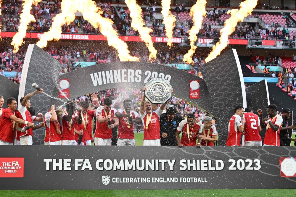 Arsenal's Norwegian midfielder Martin Odegaard holds up the trophy as Arsenal players celebrate winning the English FA Community Shield football match between Arsenal and Manchester City at Wembley Stadium, in London, August 6, 2023. (Photo by Glyn KIRK / AFP) / NOT FOR MARKETING OR ADVERTISING USE / RESTRICTED TO EDITORIAL USE
