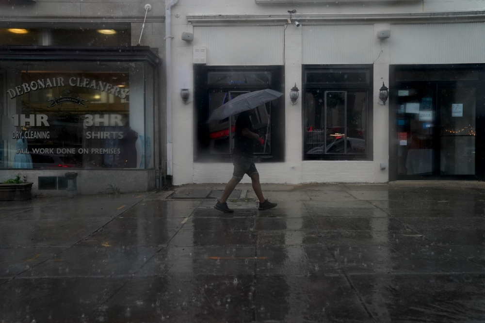 A pedestrian carries an umbrella while walking through rain in Washington, DC, on August 7, 2023. Photo by Stefani Reynolds / AFP