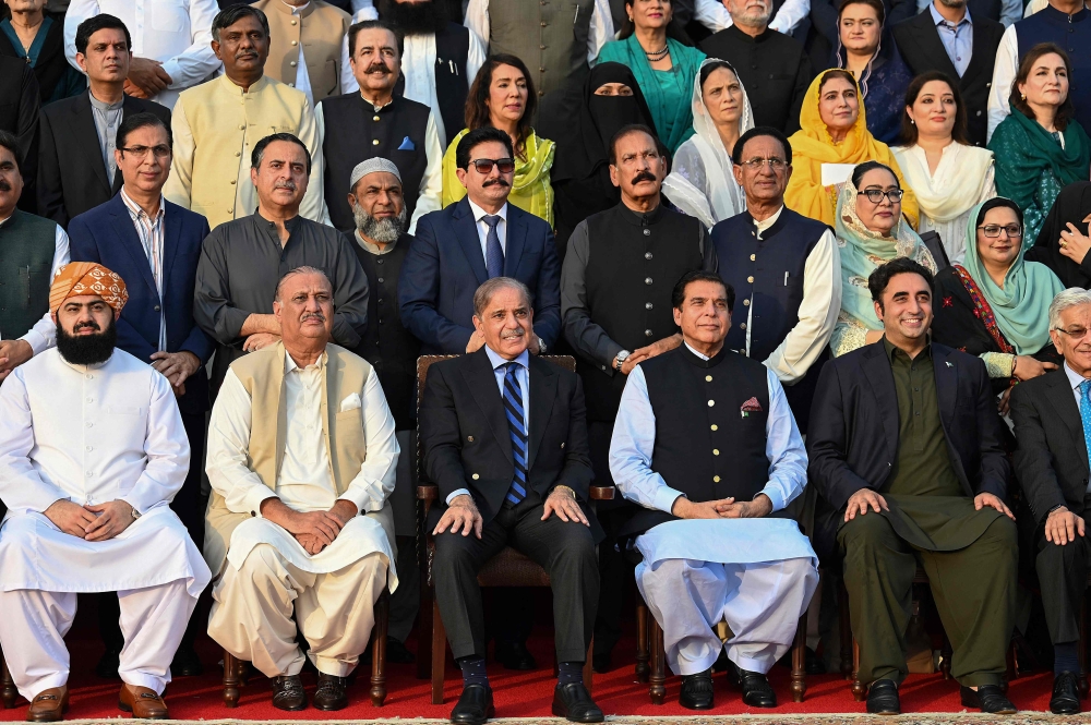 Pakistan's Prime Minister Shehbaz Sharif (3L in front row) poses for a photograph with parliamentarians after current last session of National Assembly outside the parliament house building in Islamabad on August 9, 2023. (Photo by Aamir QURESHI / AFP)
