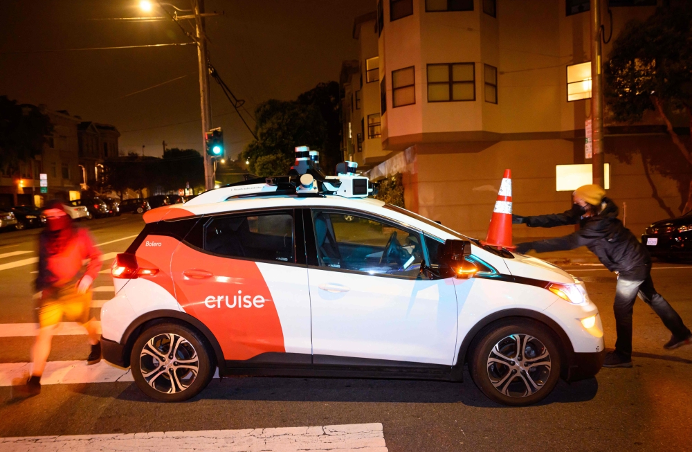 Members of SafeStreetRebel, a group of anonymous anti-car activists, place a cone on a self-driving robotaxi to disable it in San Francisco, California on July 11, 2023. Photo by Josh Edelson / AFP

