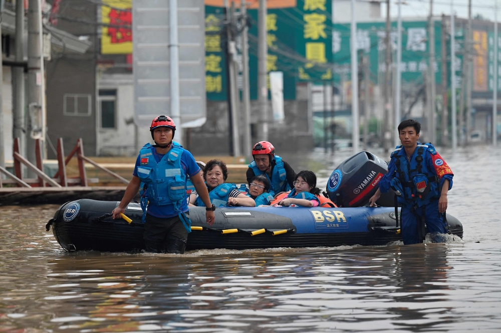 Rescue team personnel wade in a flooded road as they evacuate residents following heavy rains in Zhuozhou, in northern China痴 Hebei province on August 2, 2023. Photo by Jade Gao / AFP