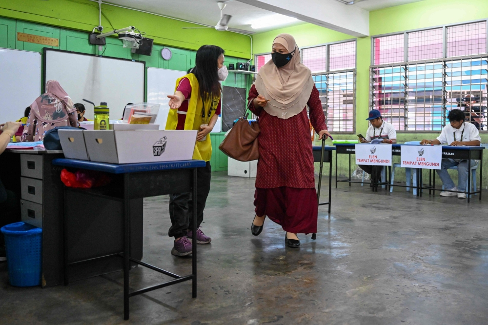 A woman (centre R) carries her ballot paper before casting her vote during the state election at a polling station in Selayang in Malaysia's Selangor state on August 12, 2023. (Photo by Mohd Rasfan / AFP)
