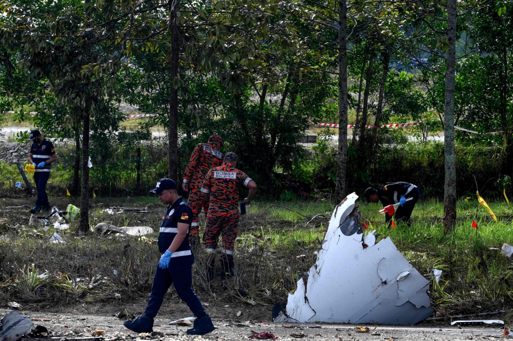 Members of the fire and rescue department inspect the crash site of a plane in Shah Alam, Malaysia's Selangor state on August 17, 2023. Photo by Muhammad Lutfi / AFP