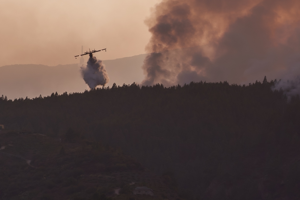 A hydroplane drops water in the area of Guilmar over a huge wildfire raging through forested areas that surround the Mount Teide volcano natural park, on the Canary island of Tenerife, on August 21, 2023. Photo by CESAR MANSO / AFP