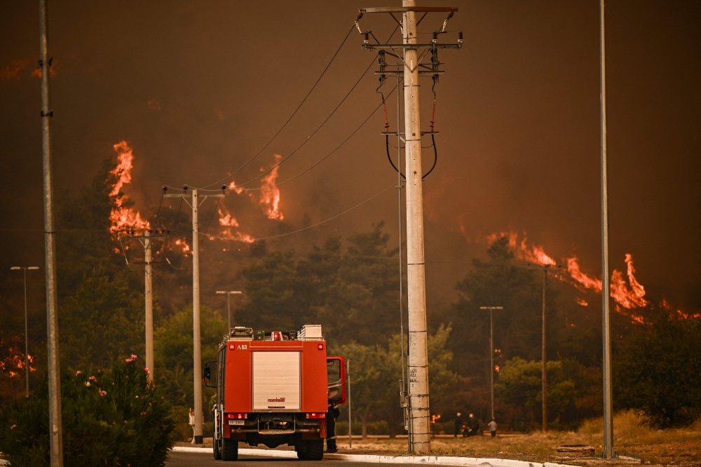 A firefighting vehicle rides on a road during a wildfire in Chasia in the outskirts of Athens on August 22, 2023. (Photo by Angelos Tzortzinis / AFP)