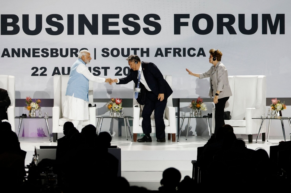 Prime Minister of India Narendra Modi (left) shakes hands with China's Minister of Commerce Wang Wentao as Former President of Brazil and chair of the New Development Bank Dilma Rousseff (right) looks on during the 2023 BRICS Summit at the Sandton Convention Centre in Johannesburg on August 22, 2023. (Photo by Marco Longari / AFP)