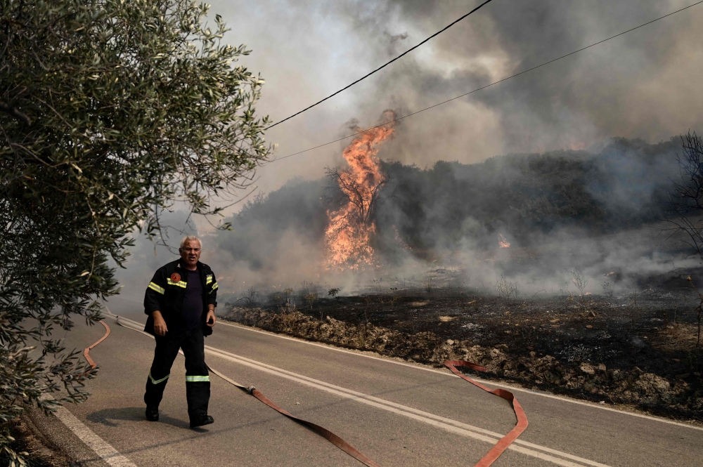 A Greek firefighter battles a forest fire spreading in Dikella near Alexandroupoli, northern Greece, on August 23, 2023. Photo by Sakis MITROLIDIS / AFP