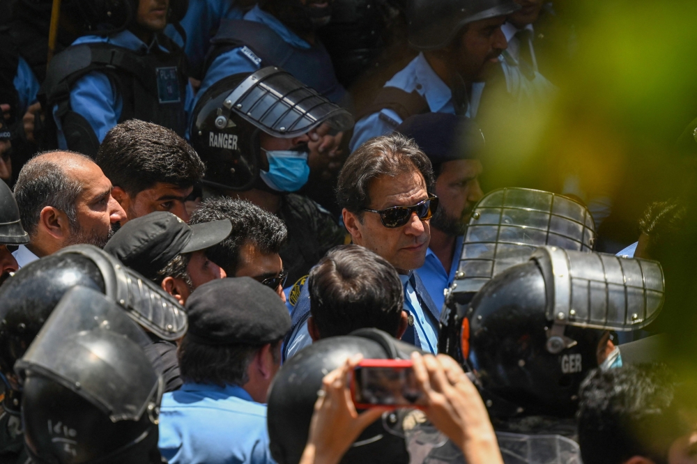 File photo: Policemen escort Pakistan's former Prime Minister Imran Khan (centre) as he arrives at the high court in Islamabad on May 12, 2023. (Photo by Aamir Qureshi / AFP)