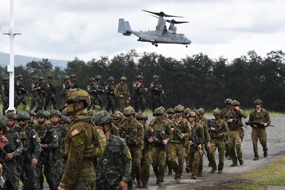 Philippine and Australian soldiers march in formation while a US marines V-22 Osprey hovers above during military exercise Alon (wave), a joint amphibious landing drill held at a naval base in San Antonio town in Zambales province, north of Manila on August 25, 2023. Photo by TED ALJIBE / AFP