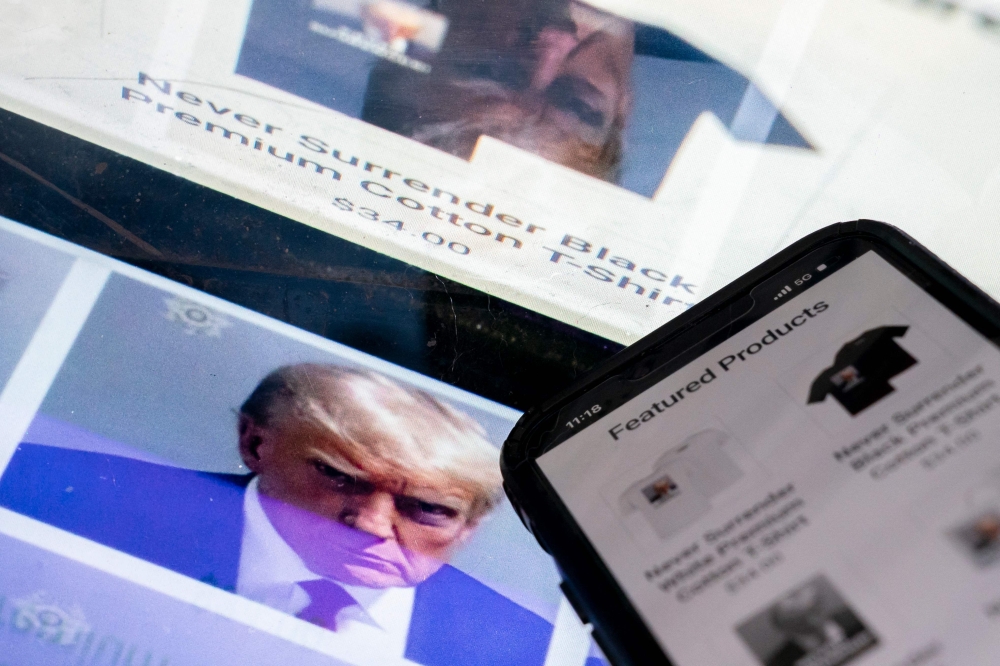 This photo illustration created in Washington, DC, on August 27, 2023, shows the mugshot of former US President Donald Trump next to a website called Trump Save America JFC, a joint fundraising committee on behalf of Donald J. Trump for President 2024, which is selling merchandise bearing his mugshot. (Photo by Stefani Reynolds / AFP)