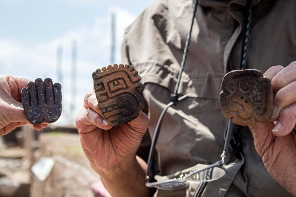 Handout picture released by the Peruvian Ministry of Culture on August 27, 2023 showing archaeologists holding pottery pieces found at a 3,000-year-old priest's tomb, found by a group of Japanese and Peruvian archaeologists under a ceremonial site at the Pacopampa archeological site, in Cajamarca, northeast of Peru. (Photo by Handout / Peruvian Ministry of Culture / AFP) 