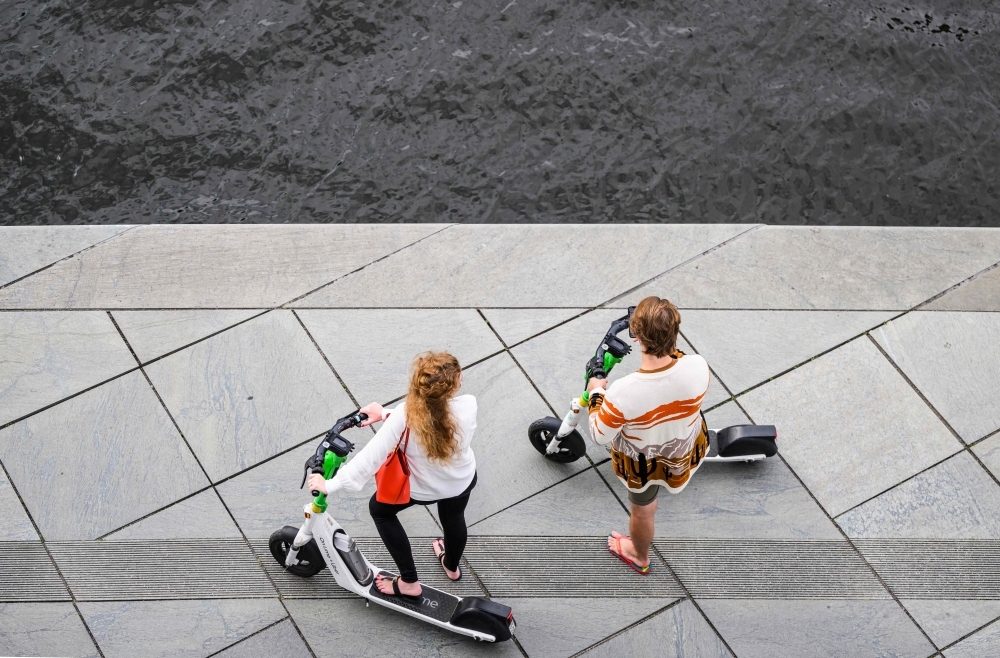 A couple uses battery-powered electric scooters from a sharing company on the banks of the river Spree in Berlin on August 27, 2023. (Photo by John MacDougall / AFP)
 