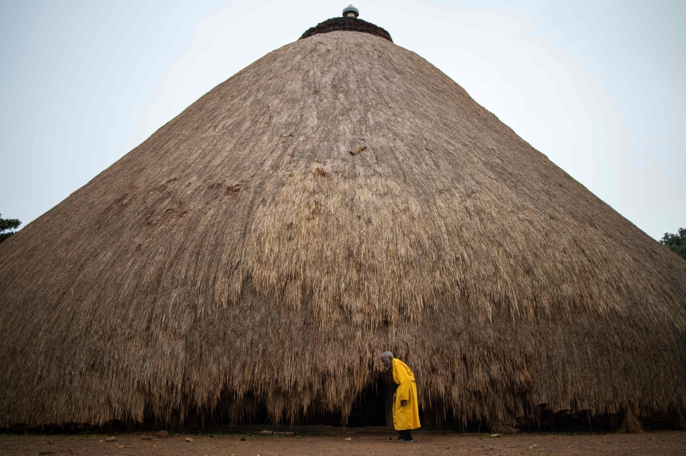A traditional guard stands in front of one of the buildings belonging to the Kasubi Royal Tombs in Kampala, Uganda on June 13, 2023. (Photo by Stuart Tibaweswa / AFP)