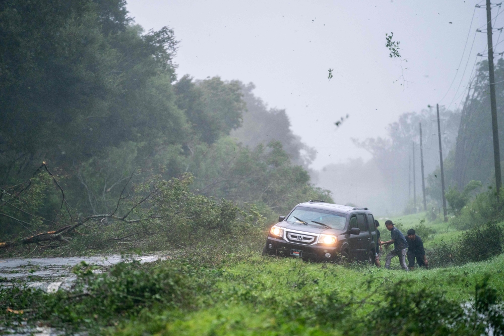 People work to free a vehicle stuck on the shoulder amid storm debris as Hurricane Idalia crosses the state on August 30, 2023 near Mayo, Florida. (Photo by Sean Rayford / GETTY IMAGES NORTH AMERICA / Getty Images via AFP)
