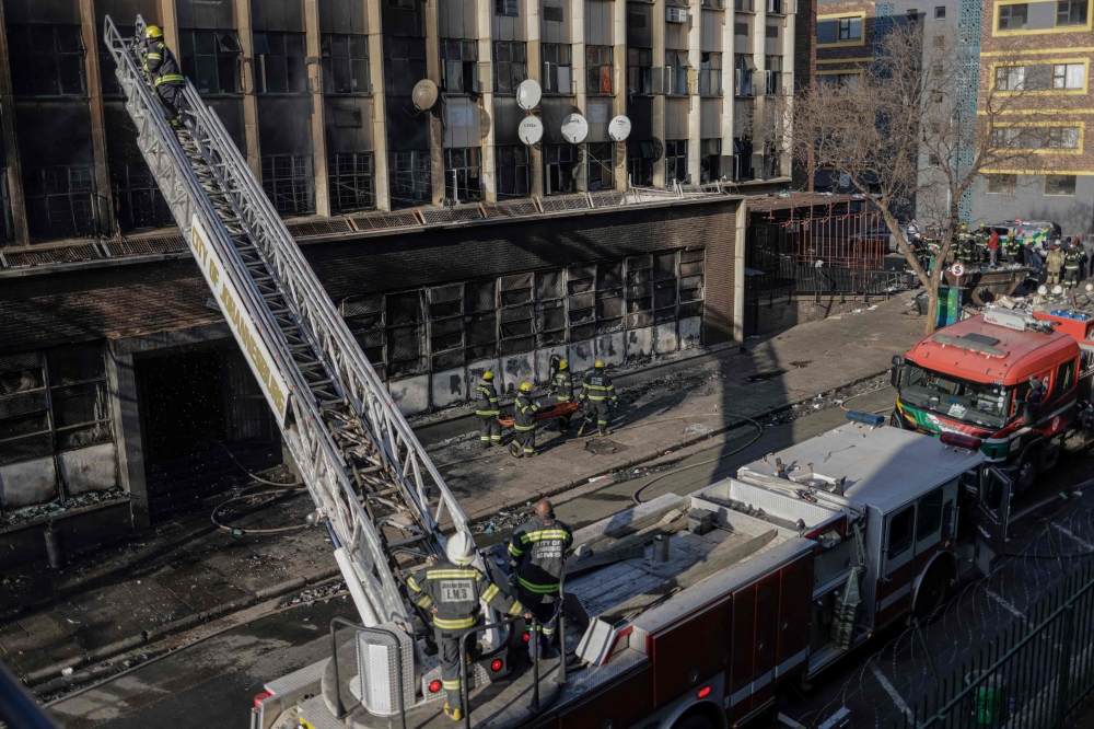 Firefighters work at the scene of a fire in Johannesburg on August 31, 2023. (Photo by Michele Spatari / AFP)