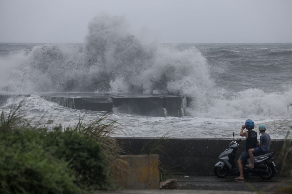 People watch huge waves in Yilan as Typhoon Haikui makes landfall in eastern Taiwan on September 3, 2023. (Photo by I-Hwa Cheng / AFP)
