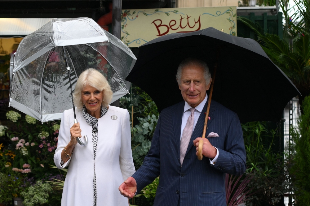 Britain's King Charles III and his wife Queen Camilla pose as they arrive to visit the central Paris Flower Market. (Photo by Daniel Leal / Pool / AFP)