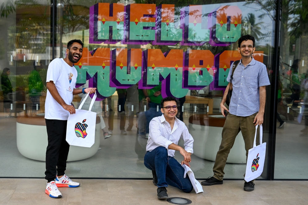 People pose outside the new Apple retail store during a media preview on the eve of its opening in Mumbai on April 17, 2023. (Photo by Punit Paranjpe / AFP)

