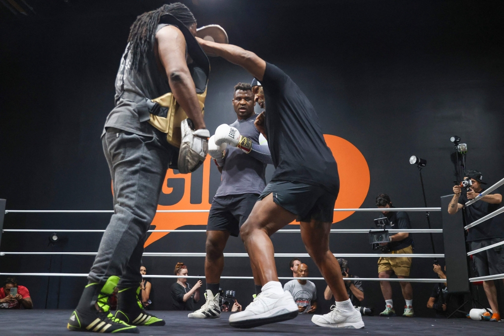 Cameroonian-French mixed martial arts star and boxer Francis Ngannou (C) watches as Dewey Cooper spars with former US boxer Mike Tyson (R) during a training session at Ngannou痴 gym in Las Vegas, Nevada, on September 26, 2023. (Photo by Ian Maule / AFP)
