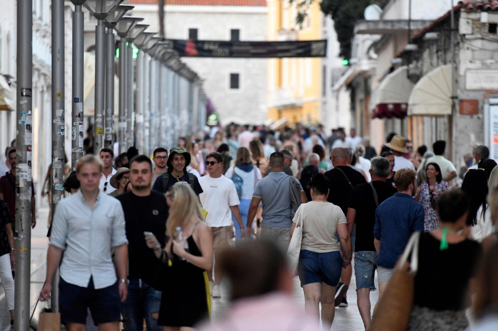 Tourists walk in a street before sunset in Split, Croatia, on September 27, 2023. (Photo by Denis Lovrovic / AFP)