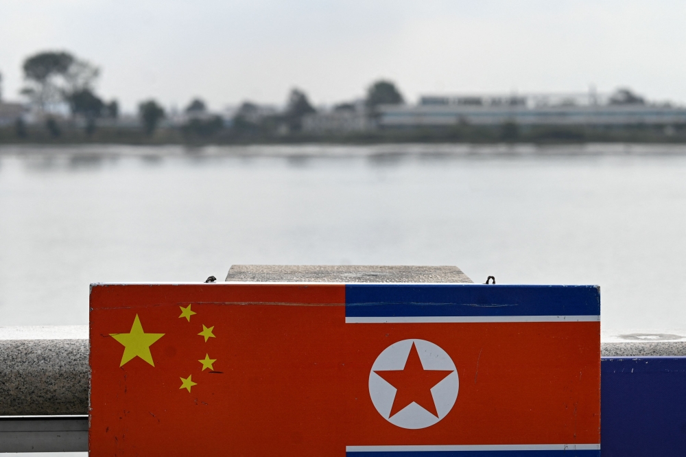 This photo taken on September 22, 2023 shows a general view of the flags of China and North Korea near the Yalu River, on the border between the North Korean town of Sinuiju and the city of Dandong, in China's northeastern Liaoning province.  (Photo by Pedro Pardo / AFP) 