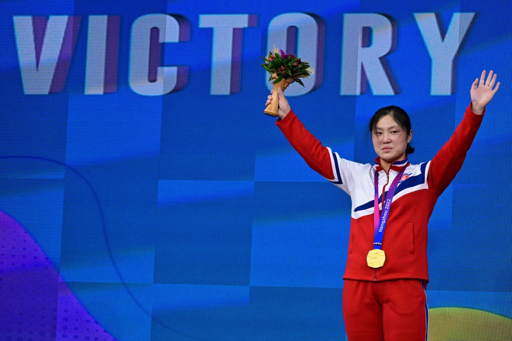 North Korea's Kim Il Gyong celebrates with her gold medal during the medal ceremony for the women's 59kg group A weightlifting competition during the Hangzhou 2022 Asian Games in Hangzhou, in China's eastern Zhejiang province on October 2, 2023. (Photo by Ishara S. Kodikara / AFP)