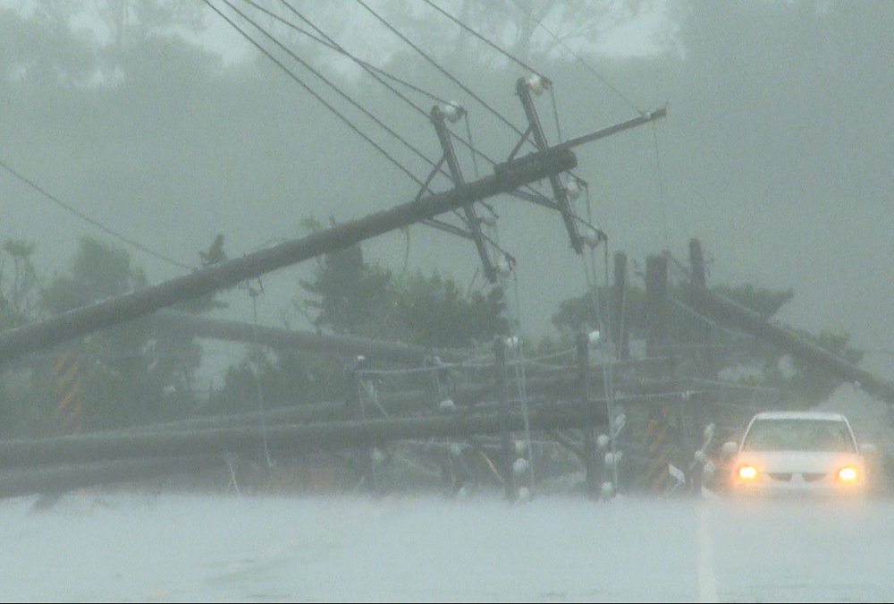 A car passes by power lines downed by the high winds from Typhoon Koinu in Taiwan's southern Pingtung County on October 5, 2023. (Photo by Sean Chang / AFP)