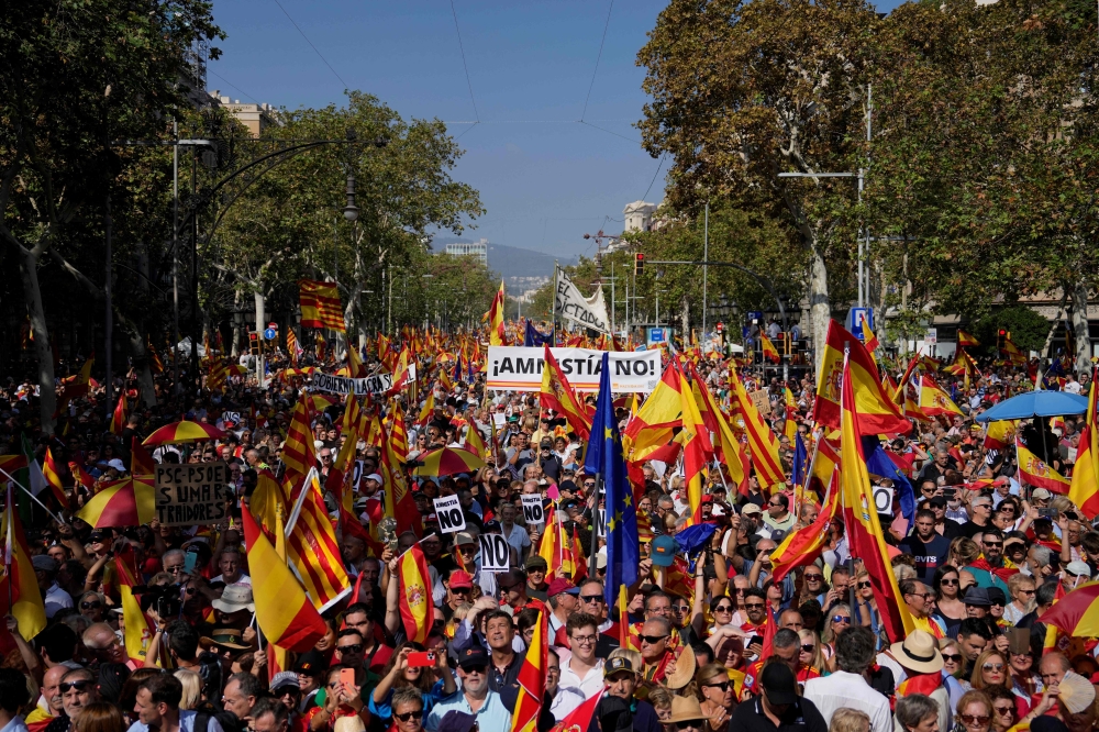 Protesters hold Spain's, EU's flags and 'No to amnesty' signs during a right-wing protest against plans to grant Catalan separatists an amnesty in order to form Spain's next government, in Barcelona on October 8, 2023.(Photo by Pau BARRENA / AFP)
