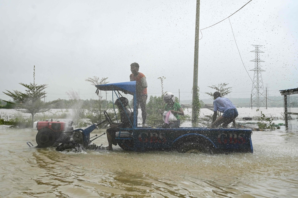 A tractor drives through a flooded street in Hpa Yar Gyi township in Myanmar's Bago region on October 9, 2023. (Photo by Sai Aung Main / AFP)
