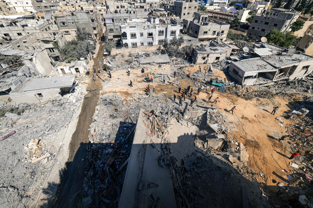 Palestinians gather to search for survivors in rubble of a collapsed building following an Israeli strike, in Khan Yunis in the southern Gaza Strip on October 14, 2023. (Photo by Mahmud Hams / AFP)