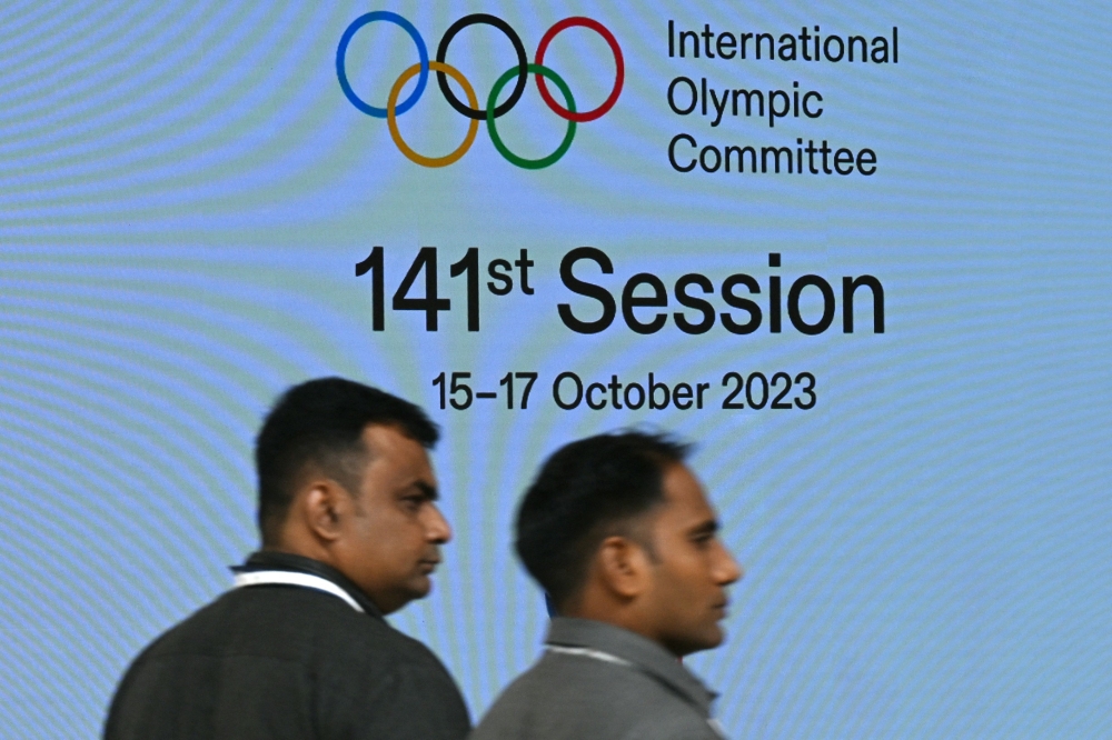 Venue staff walk past a digital screen on the first day of the 141st Session of the International Olympic Committee (IOC), in Mumbai on October 15, 2023. Photo by INDRANIL MUKHERJEE / AFP