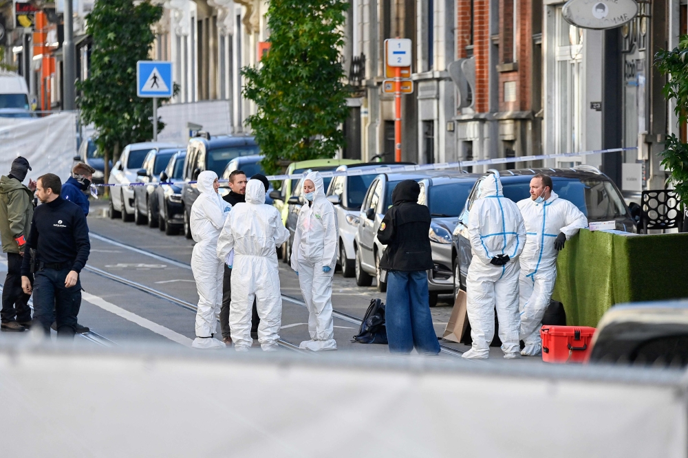Belgian police officers from the forensic service gather in the street in the Schaerbeek area of Brussels on October 17, 2023. (Photo by John Thys / AFP)